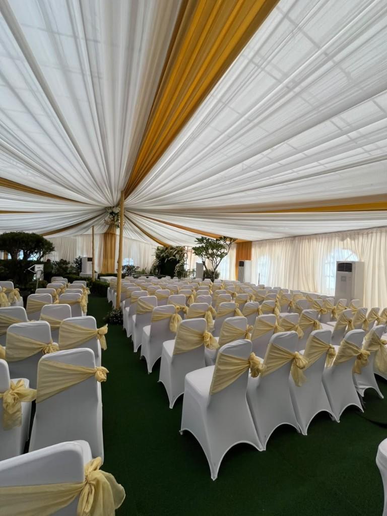 Interior tenda Paket VIP dengan draperi emas dan kursi bersarung di San Diego Hills